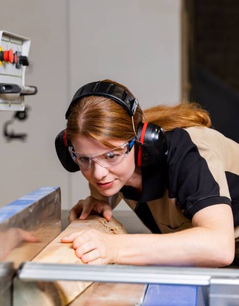 Handwerkerin an der Kreissäge mit TECWERK Schutzbrille und Gehörschutz
