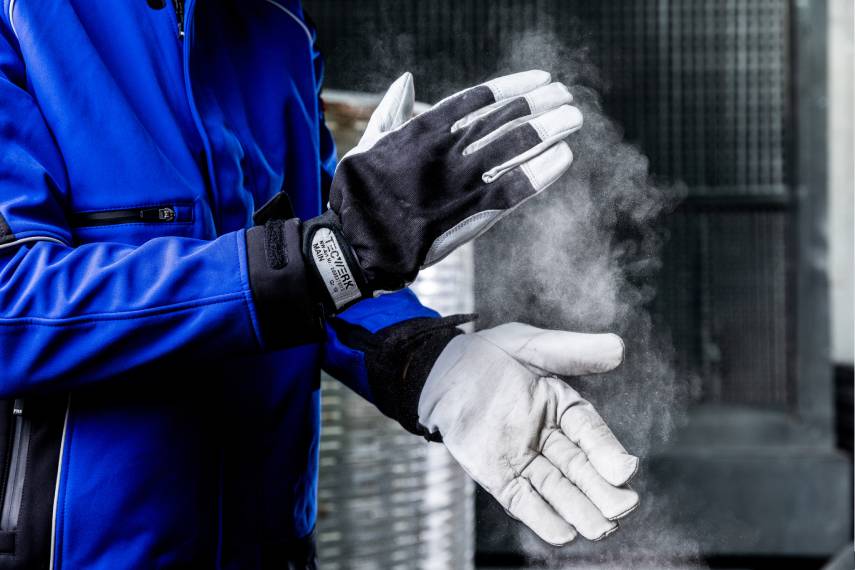 Handerker mit blauer Arbeitsjacke und TECWERK Läderschutzhandschuhen