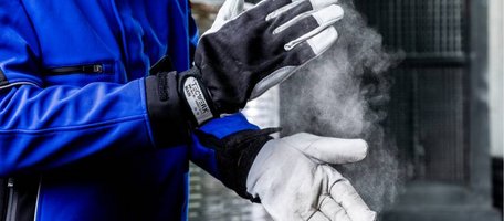 Handerker mit blauer Arbeitsjacke und TECWERK Läderschutzhandschuhen