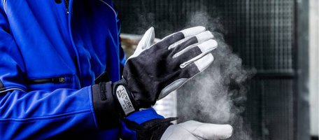 Handerker mit blauer Arbeitsjacke und TECWERK Läderschutzhandschuhen